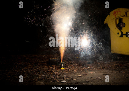 Sparks and smoke coming out of a firework exploding on a sidewalk Stock Photo