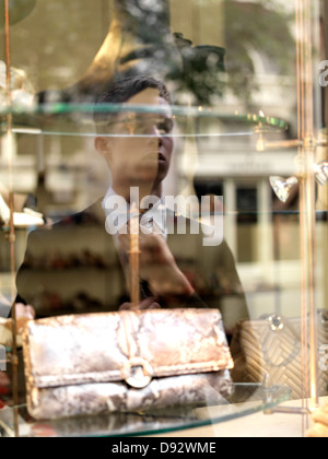 A young businessman adjusting his tie using a shop window as a mirror Stock Photo