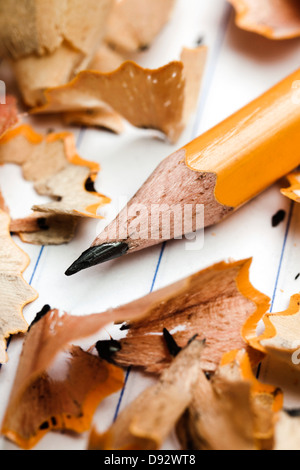 A pencil and pencil shavings atop lined notebook paper, extreme close up Stock Photo
