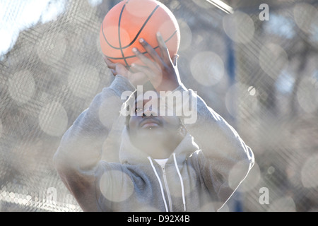 A hip young man aiming a basketball while on an outdoor basketball court Stock Photo