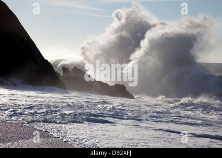 Sunlight shining on large waves crashing against rocks Stock Photo