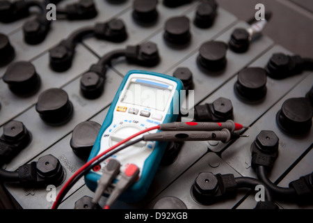 A multimeter lying on top of a battery used in solar powered energy Stock Photo