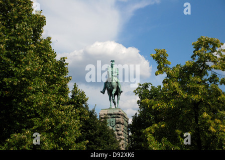 Monument to Kaiser Wilhelm at the Hohenzollern Bridge framed by trees in Cologne, Germany Stock Photo