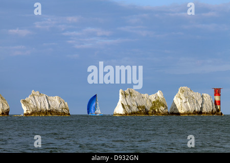 Between a rock and a hard place white sails sailing past the Needles Lighthouse Isle of Wight Stock Photo