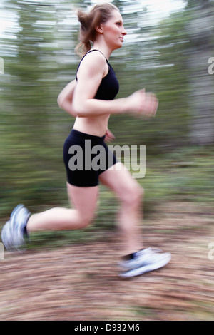 Young woman running through forest Stock Photo