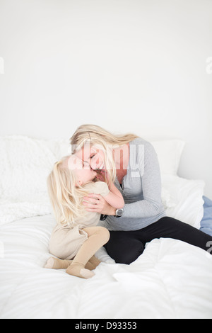 Daughter and mother hugging in bed Stock Photo