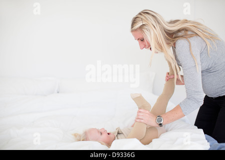 Mother playing with daughter in bed Stock Photo