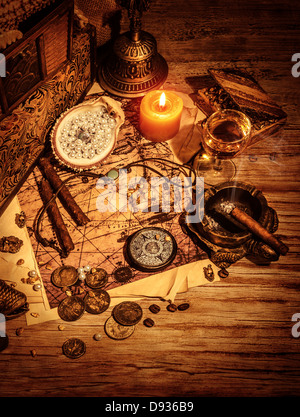 Ancient treasures border, pirates booty still life on wooden table, compass and map, golden coins and aged medallion Stock Photo