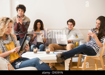 Friends using technology in living room Stock Photo