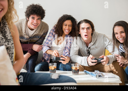 Friends playing video games in living room Stock Photo