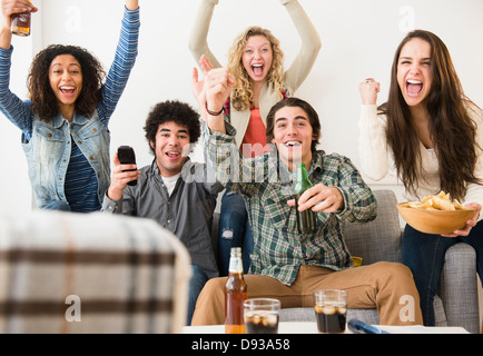 Friends cheering in living room Stock Photo