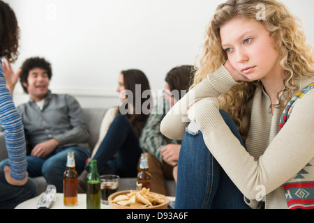 Woman sitting apart from friends Stock Photo