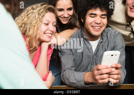 Friends using cell phone together Stock Photo
