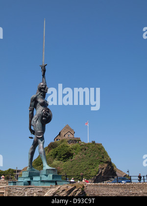 A controversial 66ft statue of a pregnant woman by artist Damien Hirst with St. Nicholas chapel behind, Ilfracombe , Devon . Stock Photo