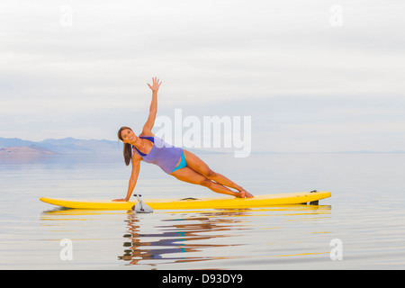Filipino woman practicing yoga on paddle board Stock Photo
