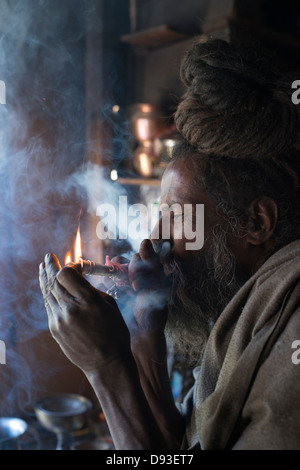 A Hindu Shaivite Sadhu (ascetic) lights a chillum (pipe) in the Himalayan district of Chamba in Himachal Pradesh, India Stock Photo