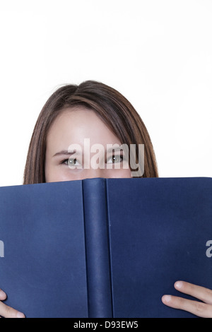 young woman peering over a hard back book Stock Photo