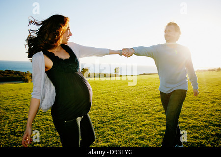 Pregnant couple playing in field Stock Photo