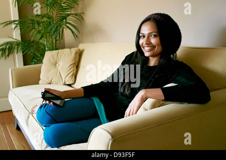 Indian woman using cell phone on sofa Stock Photo