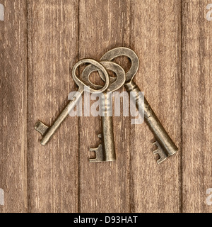 three old keys on a wooden background Stock Photo