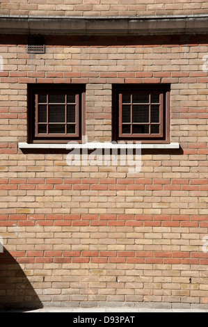 Two windows in a red and tan brick wall Stock Photo