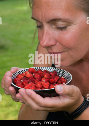 Mature woman smelling bowl of strawberry Stock Photo