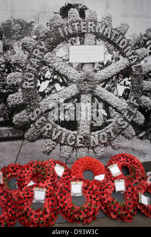 Real remembrance wreaths on the ground at the foot of a black and white vintage era photograph that shows Rotary memorial at the Cenotaph, currently hiding the real monument being renovated in London's Whitehall. Stock Photo