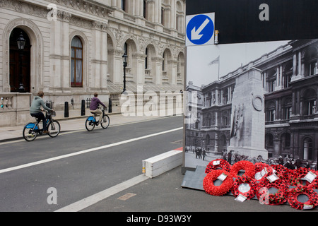 Real remembrance wreaths on the ground at the foot of a black and white vintage era photograph that shows the Cenotaph, currently hiding the real monument being renovated in London's Whitehall. In a landscape of false perspective and confusing juxtapositions between reality and the reproduction of the picture, we see the famous war memorial in central London. Stock Photo