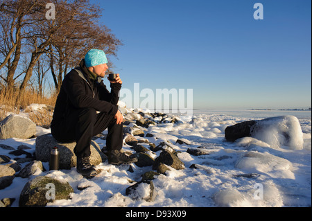 Man sitting on rock drinking coffee Stock Photo