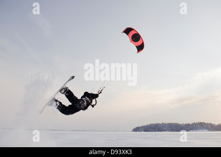 Man jumping in mid air while kiteboarding in snow Stock Photo