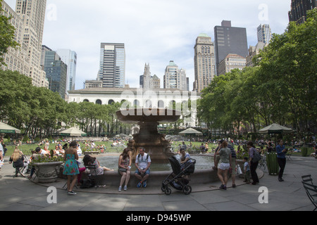 People relax in Bryant Park behind the NY Public Library along 42nd Street on a warm spring day in midtown Manhattan, NY City Stock Photo