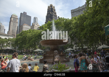 People relax in Bryant Park behind the NY Public Library along 42nd Street on a warm spring day in midtown Manhattan, NY City Stock Photo