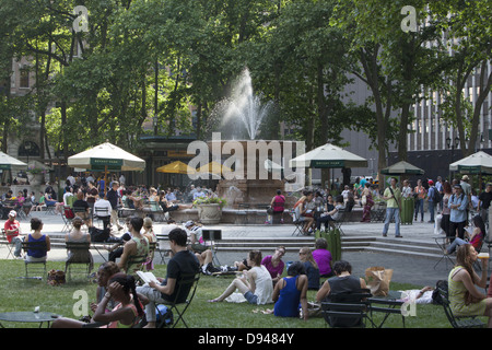 People relax in Bryant Park behind the NY Public Library along 42nd Street on a warm spring day in midtown Manhattan, NY City Stock Photo