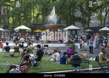 People relax in Bryant Park behind the NY Public Library along 42nd Street on a warm spring day in midtown Manhattan, NY City Stock Photo