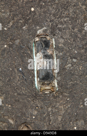 item embedded in hot tarmac road surface in sun Stock Photo