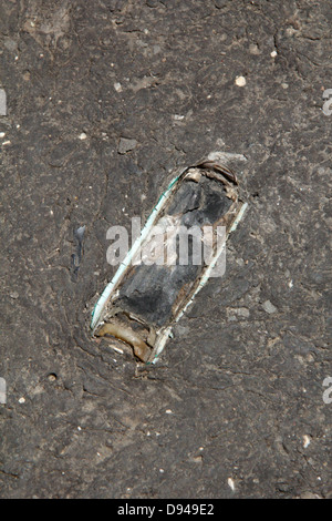 item embedded in hot tarmac road surface in sun Stock Photo