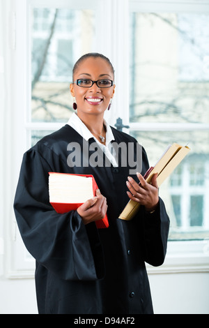 Young female lawyer working in her office with a typical law book and a file or dossier Stock Photo