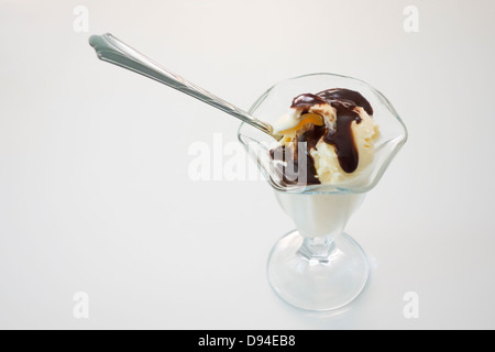 Vanilla ice cream with chocolate syrup in a dessert glass against a white background. Taken from above. Stock Photo