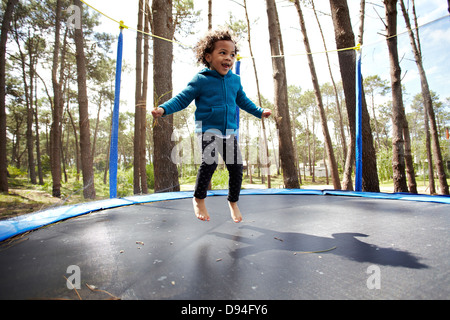 Mixed race girl jumping on trampoline Stock Photo