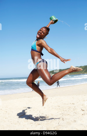 Black woman jumping for joy on beach Stock Photo