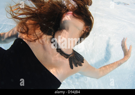 A young woman in evening dress floats underwater Model release available Stock Photo