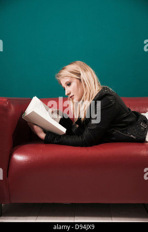 Woman Lying on Sofa and Reading a Book Stock Photo