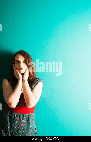 Young Woman Leaning on Wall in Studio Stock Photo