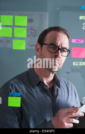Businessman Looking at Self Adhesive Notes on Glass Board in Studio