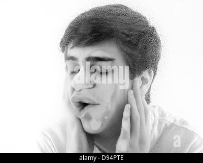 Close-up of Teenager with Face pressed against Wet Glass Stock Photo
