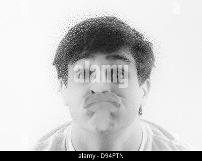 Close-up of Teenager with Face Pressed against Wet Glass Stock Photo