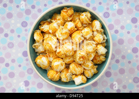 Overhead View of Caramel Popcorn in Bowl on Purple Polka Dot Background, Studio Shot Stock Photo