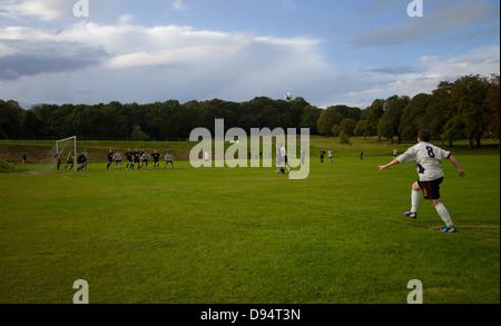a local park football match a ball is crossed in from a corner Stock Photo
