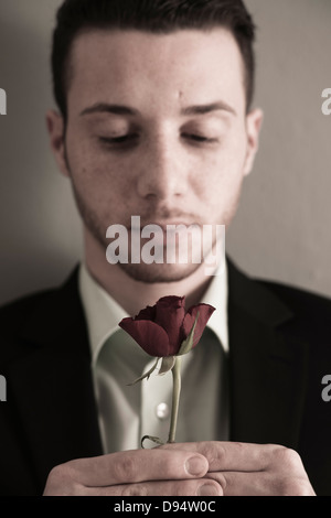 Close-up Portrait of Young Man holding Red Rose, Studio Shot Stock Photo