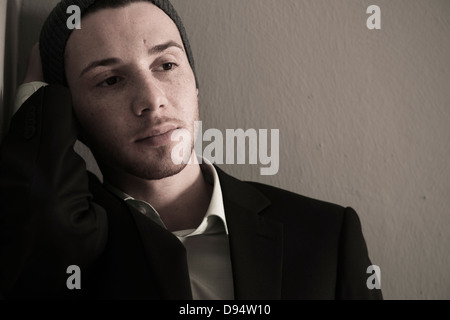 Portrait of Young Man wearing Woolen Hat and Suit Jacket, Looking to the Side, Absorbed in Thought, Studio Shot Stock Photo